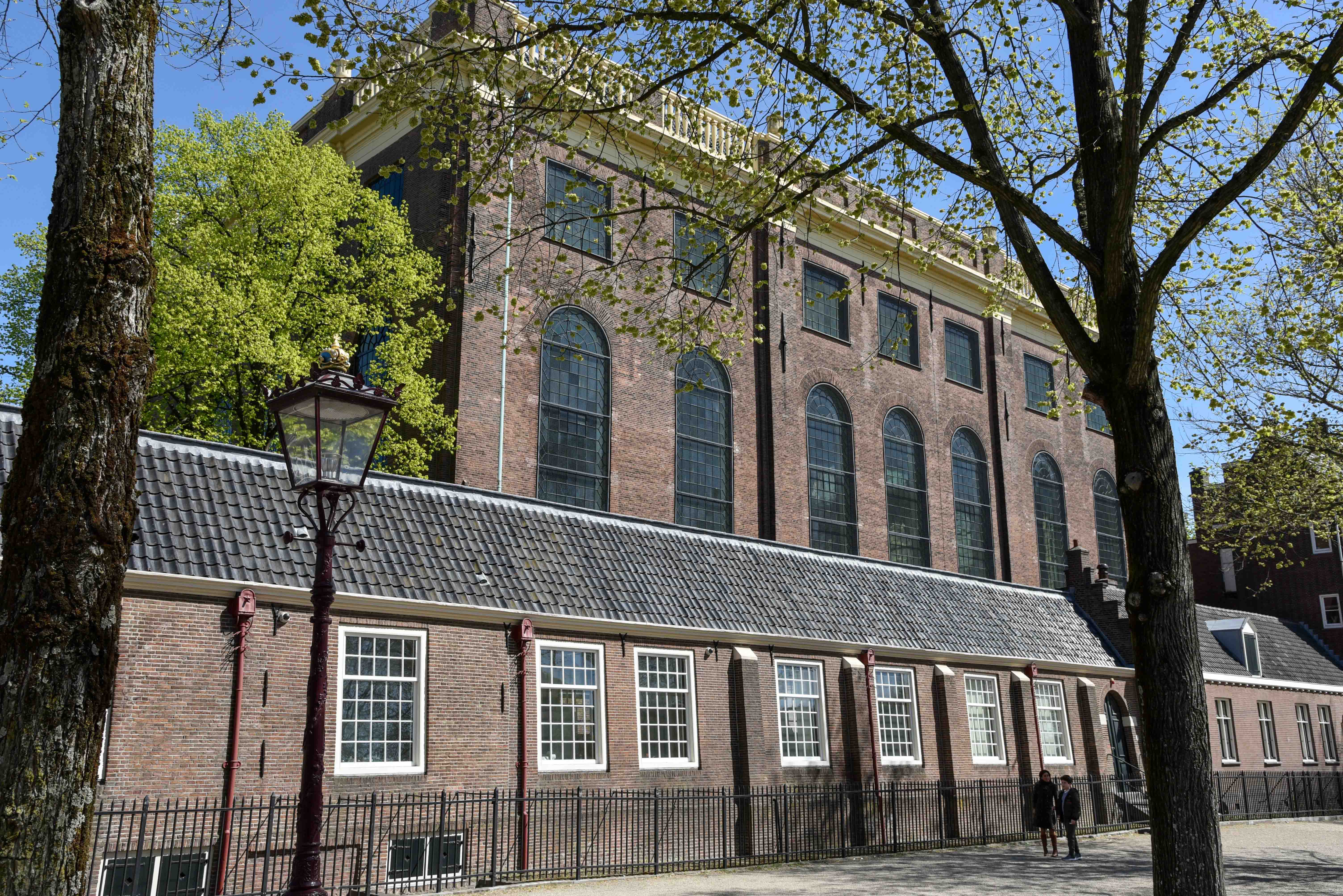 Portuguese Synagogue exterior in Amsterdam with trees and lamppost.