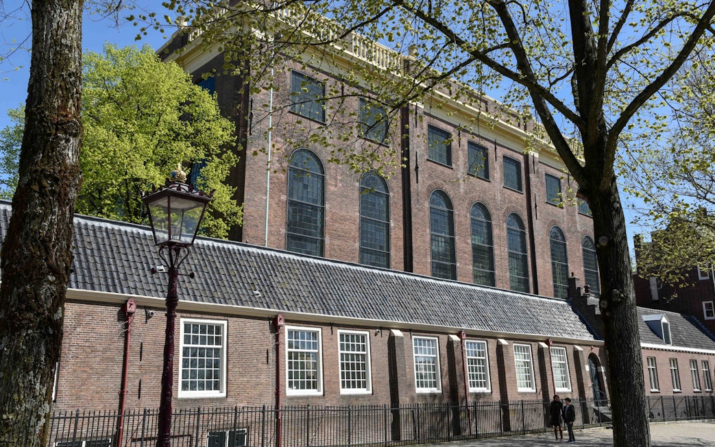 Portuguese Synagogue exterior in Amsterdam with trees and lamppost.