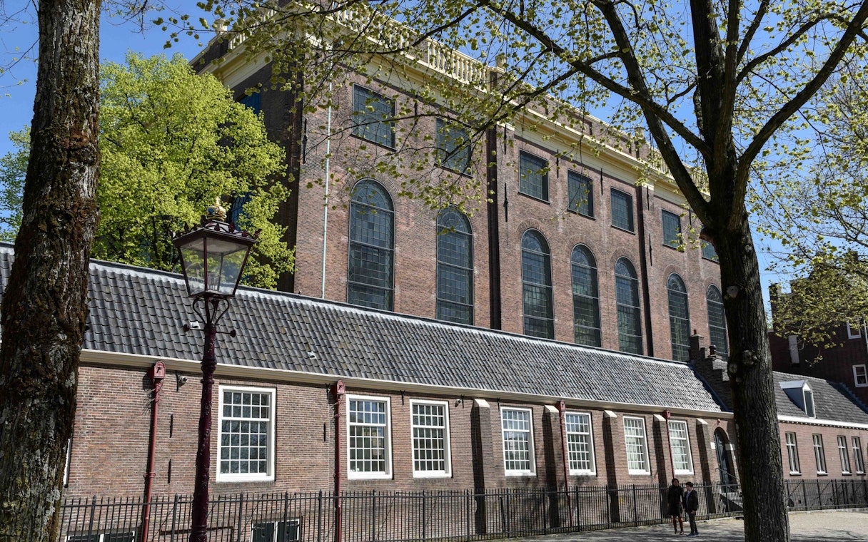 Portuguese Synagogue exterior in Amsterdam with trees and lamppost.