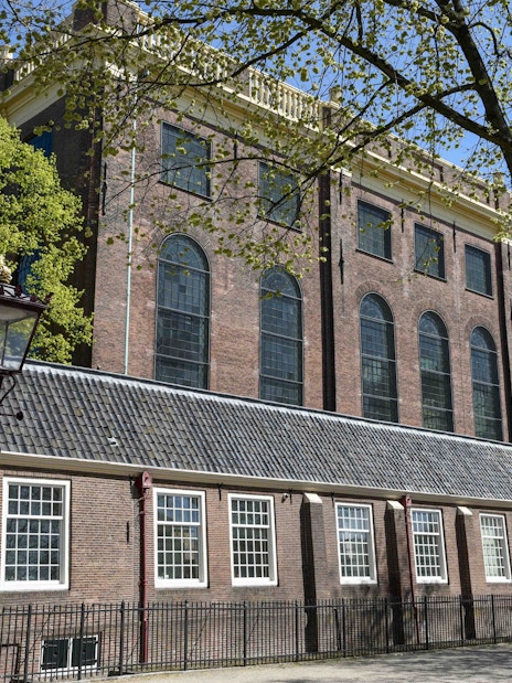 Portuguese Synagogue exterior in Amsterdam with trees and lamppost.