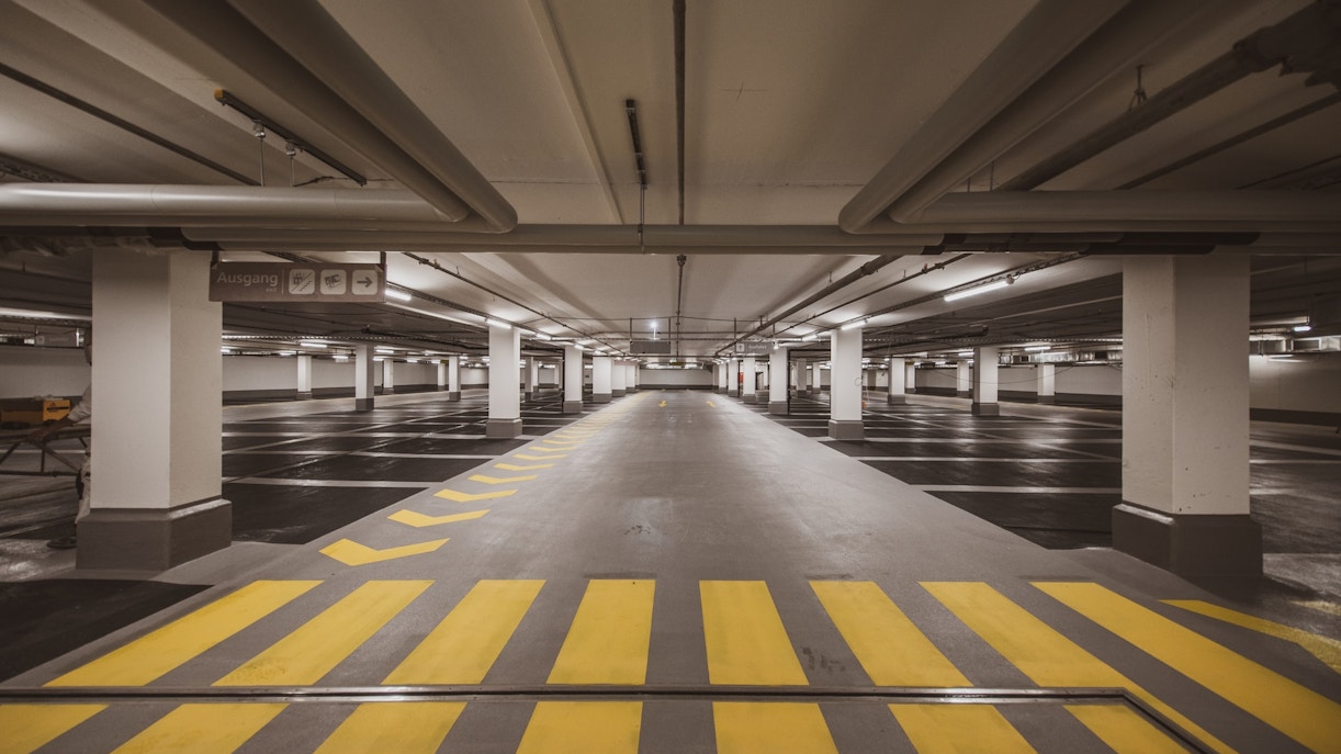 Underground parking garage with marked spaces and directional signs.