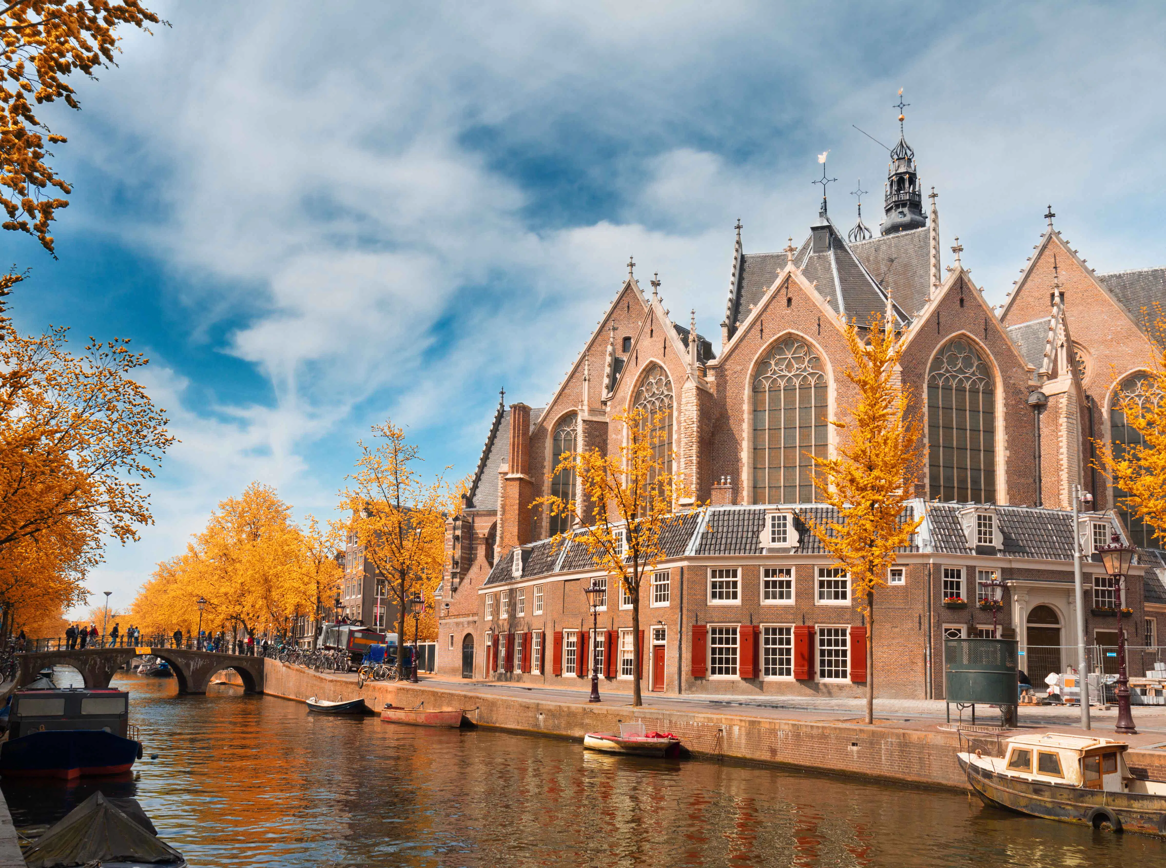 Oude Kerk in Amsterdam with canal and autumn trees.