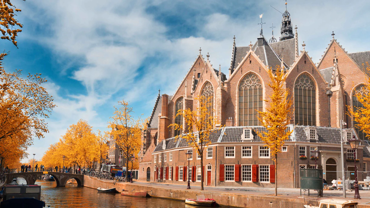 Oude Kerk in Amsterdam with canal and autumn trees.