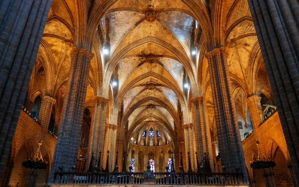 Interior view of Sagrada Familia crypt with vaulted ceilings and stained glass windows.