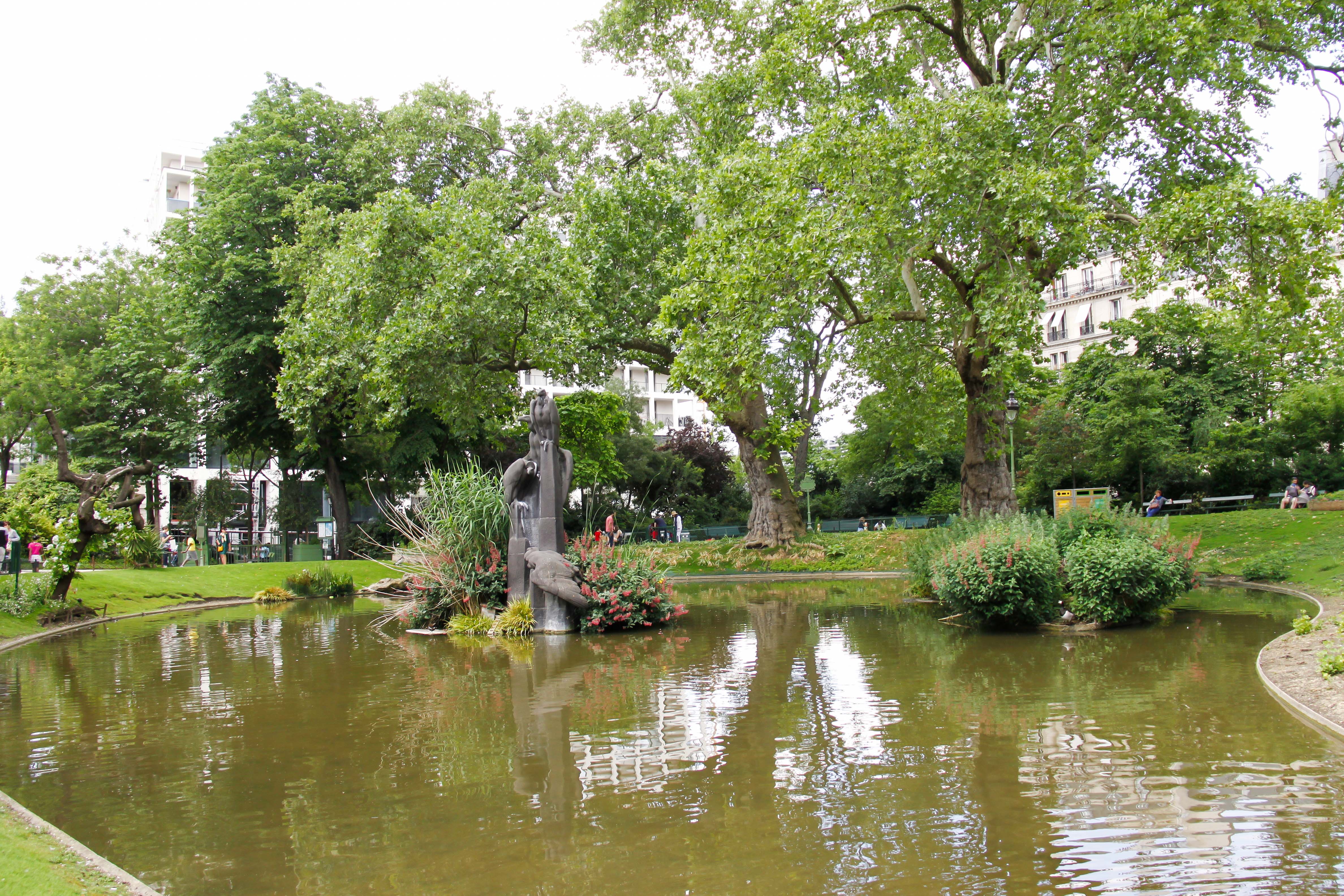 Square des Batignolles park in Paris with lush greenery and a tranquil pond.