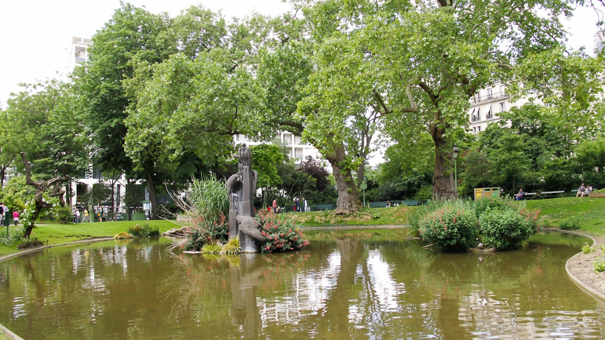 Square des Batignolles park in Paris with lush greenery and a tranquil pond.