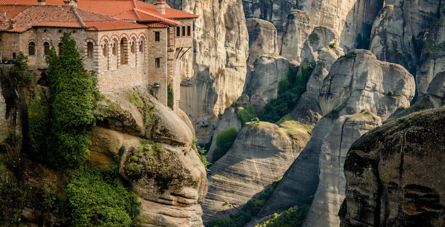 Monastery perched on a cliff in Meteora, Greece, surrounded by rock formations.