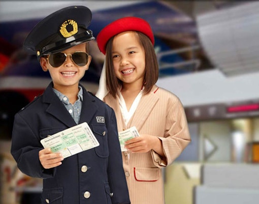 Children in pilot and flight attendant costumes holding tickets at KidZania Dubai.