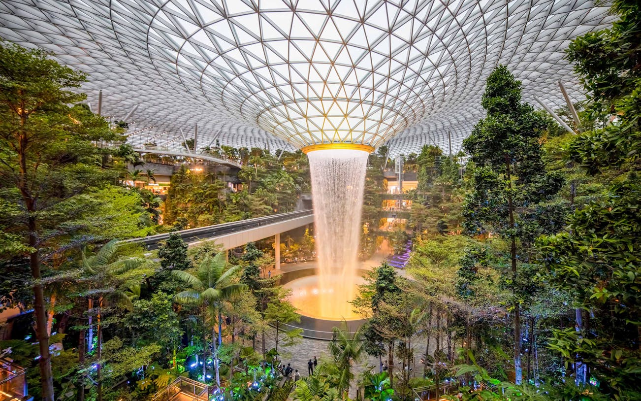Jewel Changi Airport indoor waterfall surrounded by lush greenery in Singapore.