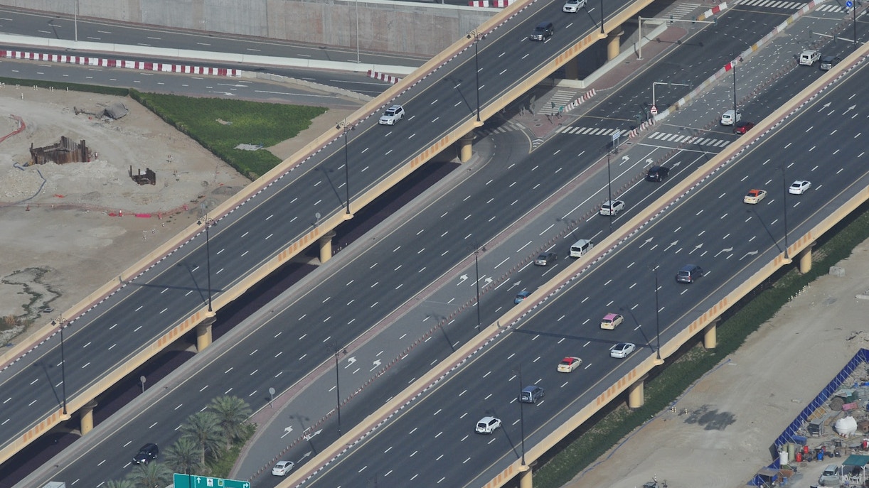 Aerial view of a multi-lane highway in Dubai with cars and palm trees.