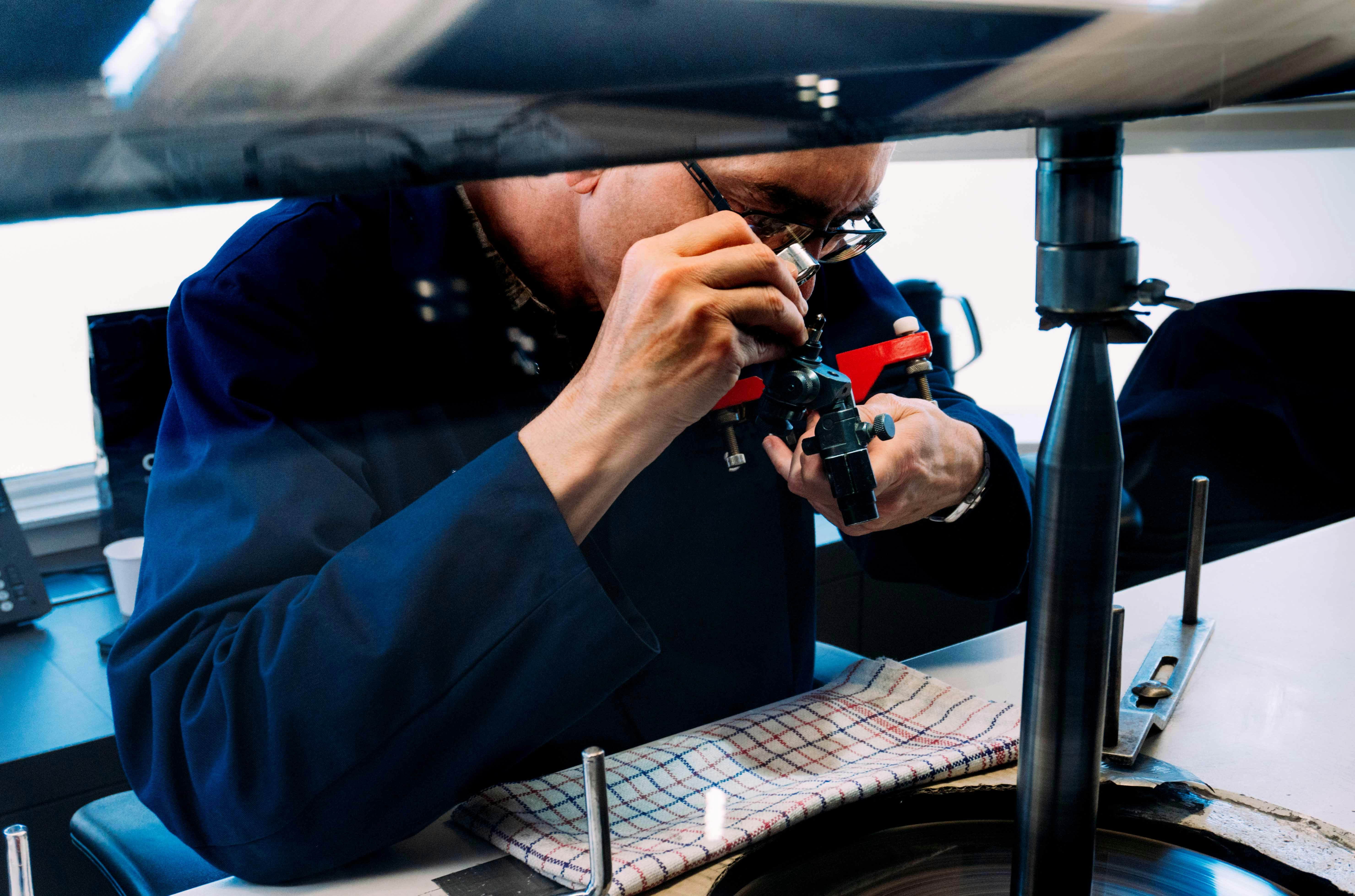 Diamond cutter examining gemstone at GASSAN Diamonds Factory, Amsterdam.
