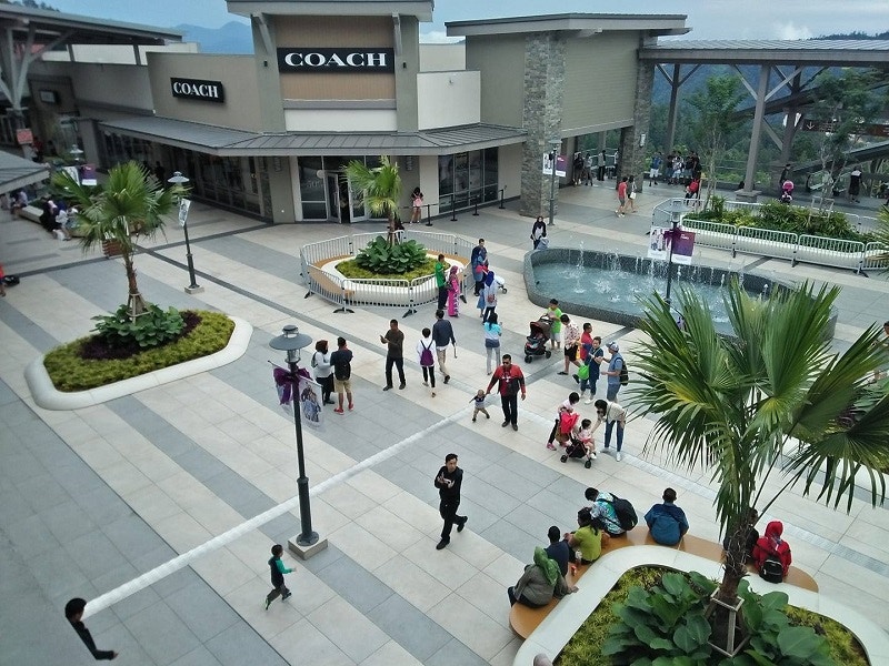 Genting Highlands Premium Outlets courtyard with shoppers and fountain.