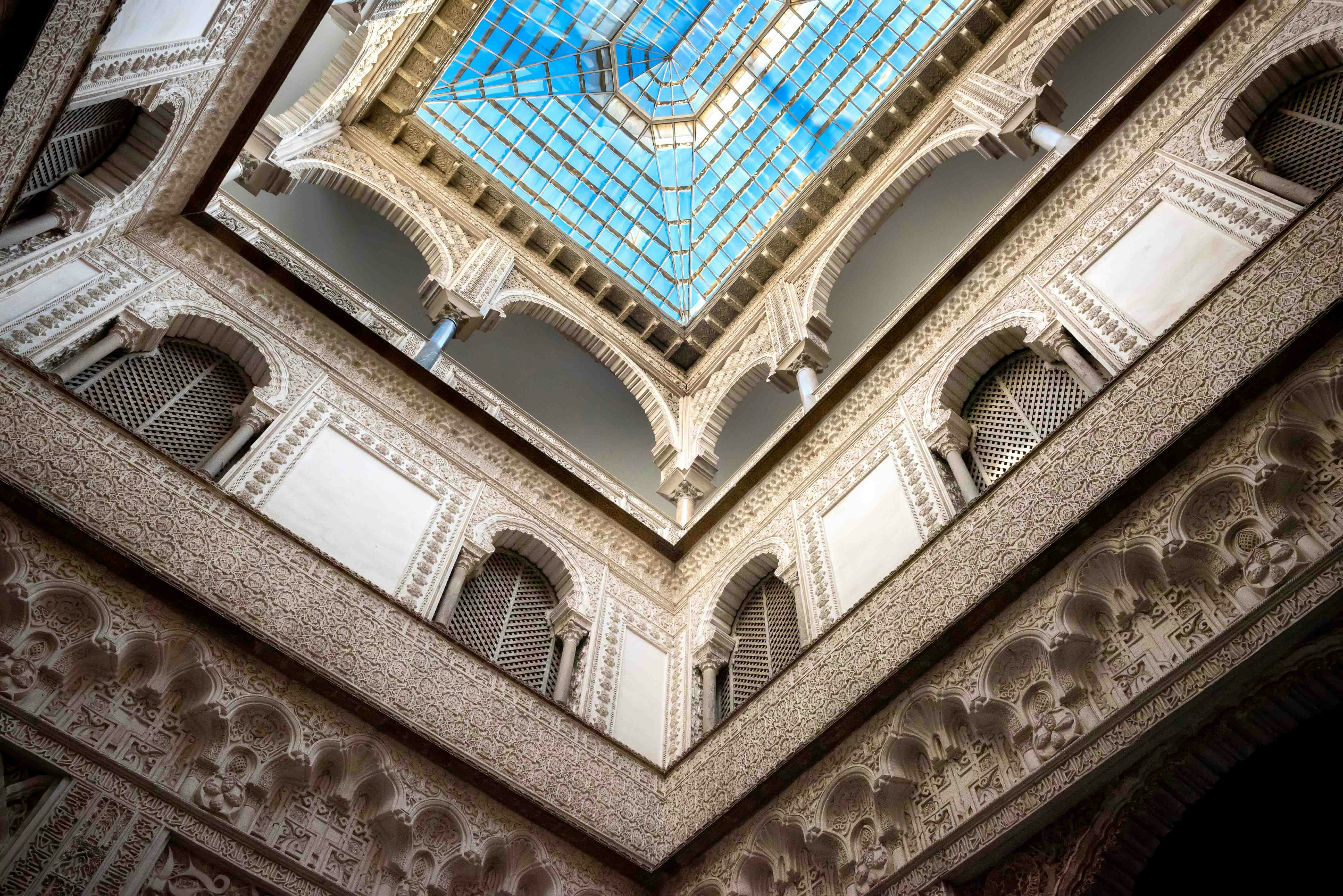 Alcazar of Seville courtyard with intricate arches and lush gardens.