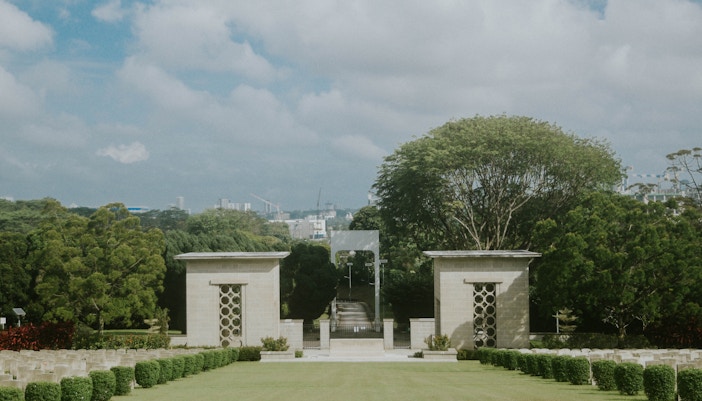 Kranji War Memorial in Singapore with rows of white gravestones and lush green surroundings.