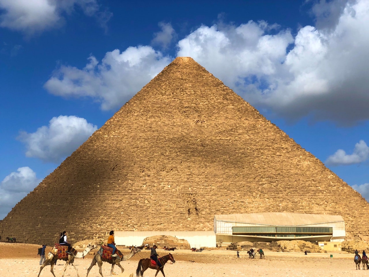 Pyramids of Giza with tourists on camels in front of Khufu Pyramid, Egypt.