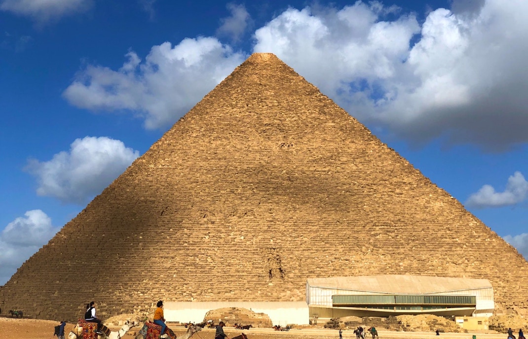 Pyramids of Giza with tourists on camels in front of Khufu Pyramid, Egypt.