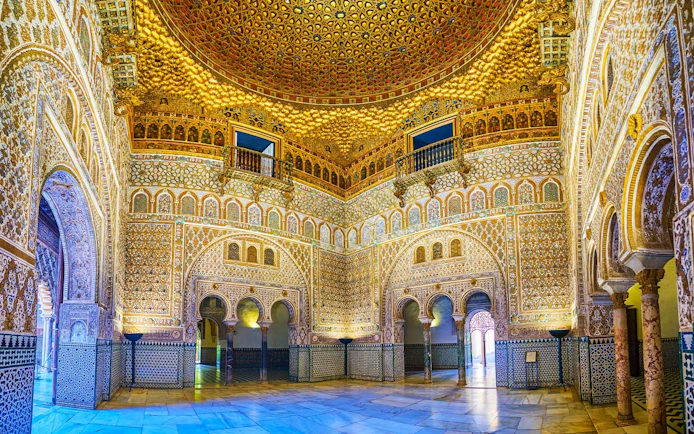 Tourists exploring the ornate archways of the Royal Alcazar of Seville on a guided tour.