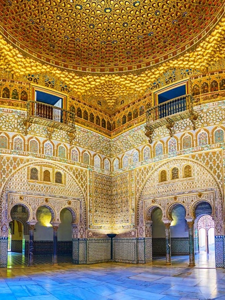 Tourists exploring the ornate archways of the Royal Alcazar of Seville on a guided tour.