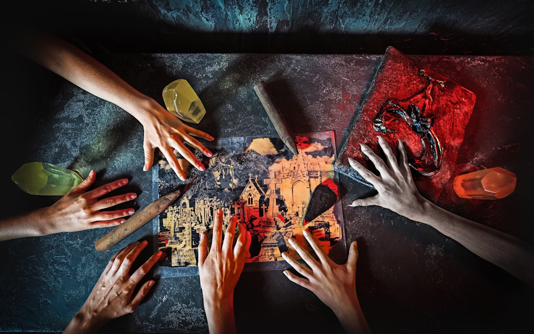 Hands reaching over a map with knives and crystals, part of Saw: The Experience in London.