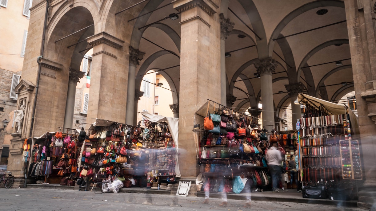 San Lorenzo Market stalls with shoppers browsing goods in Florence, Italy.