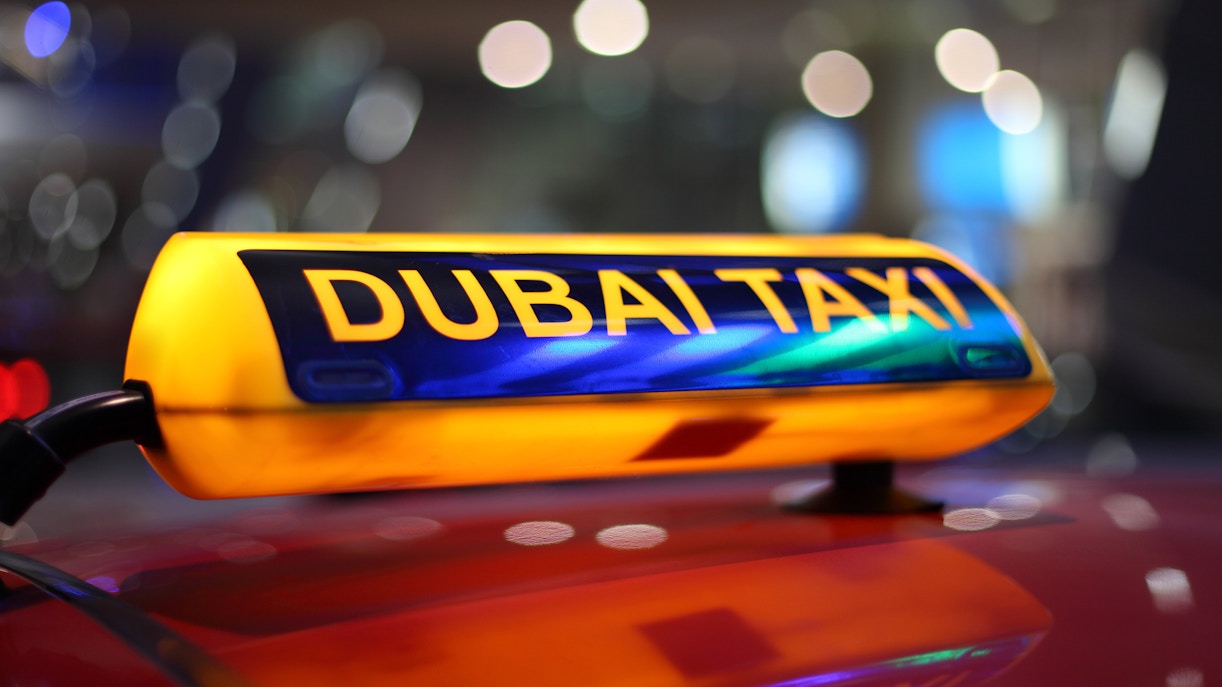 Dubai taxi sign illuminated at night.
