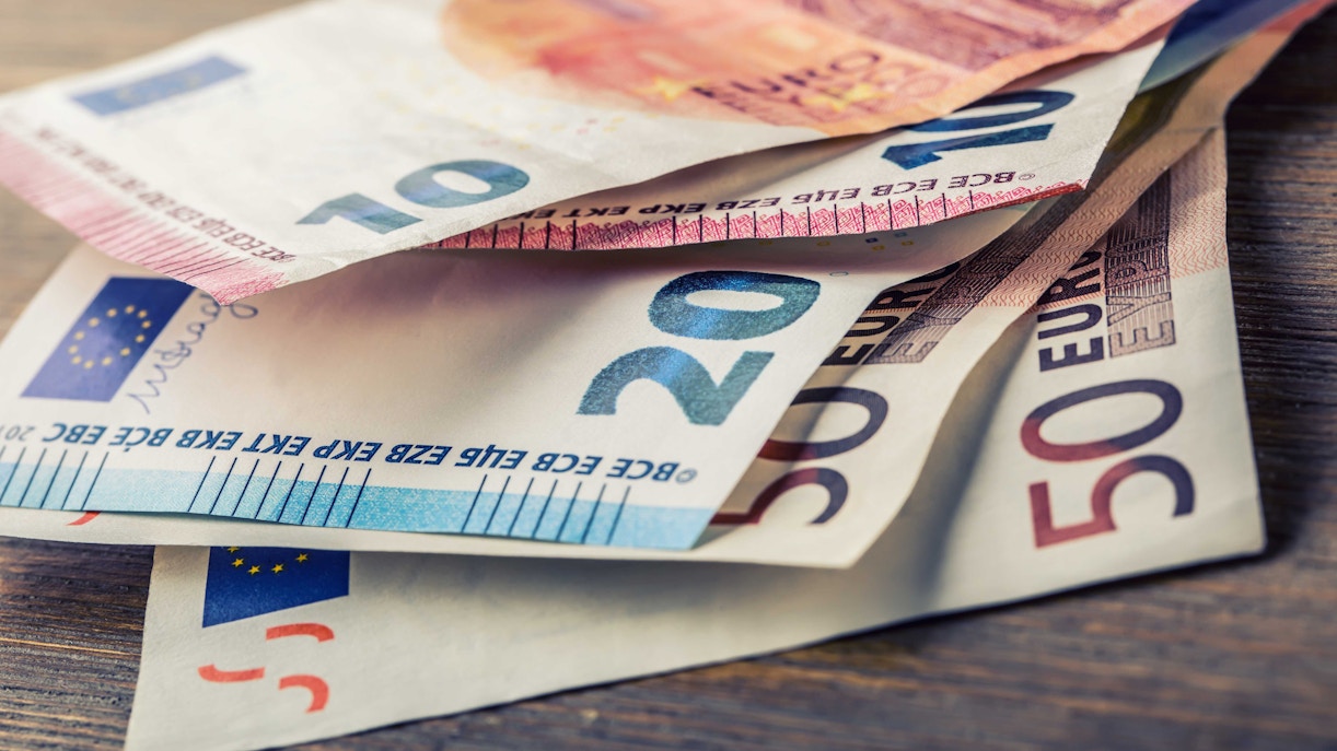 Euro banknotes on a wooden table, representing shopping in Florence.