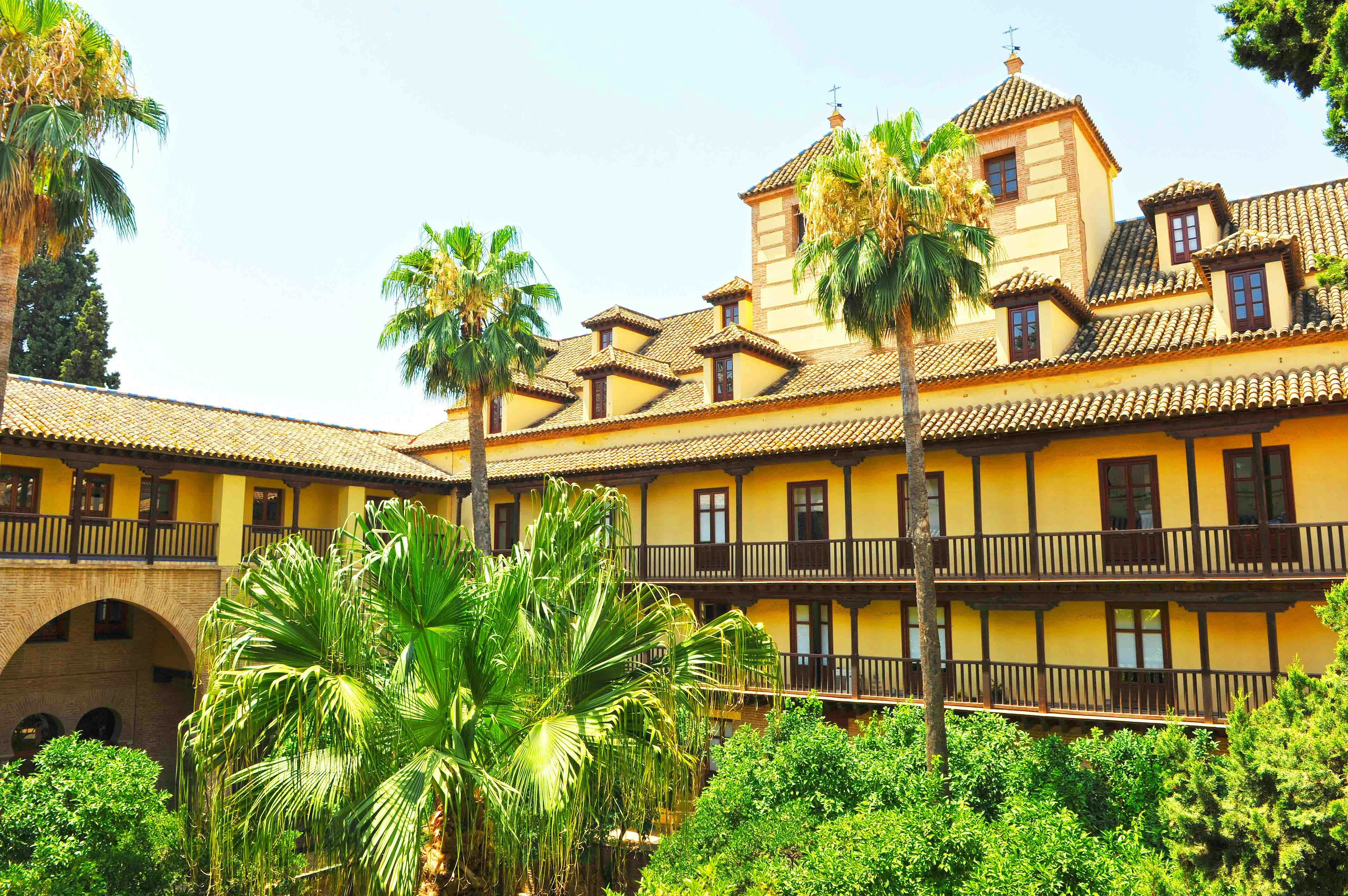 Alcazar of Seville courtyard with intricate arches and lush gardens.