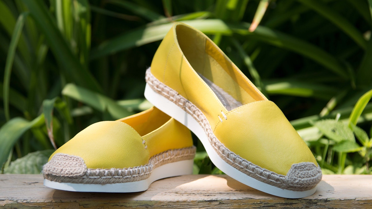Yellow espadrilles on a wooden bench, perfect for summer shopping in Madrid.