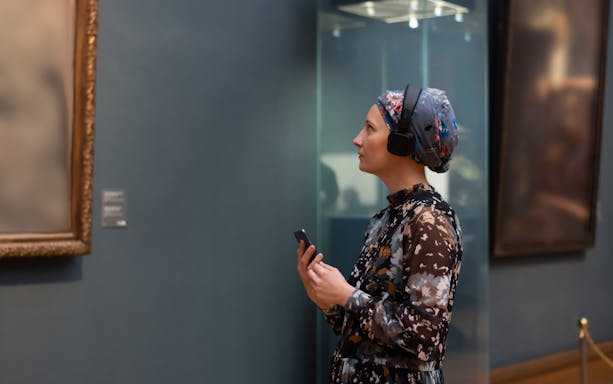 Visitor with audio guide at Picasso Museum exhibit.