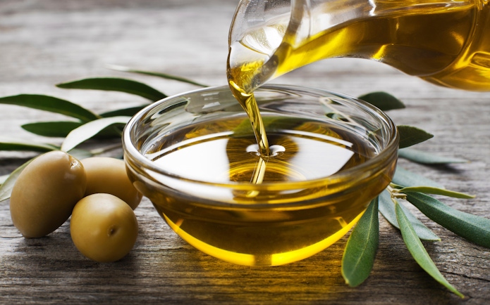 Pouring olive oil into a bowl with olives and leaves, Madrid shopping.