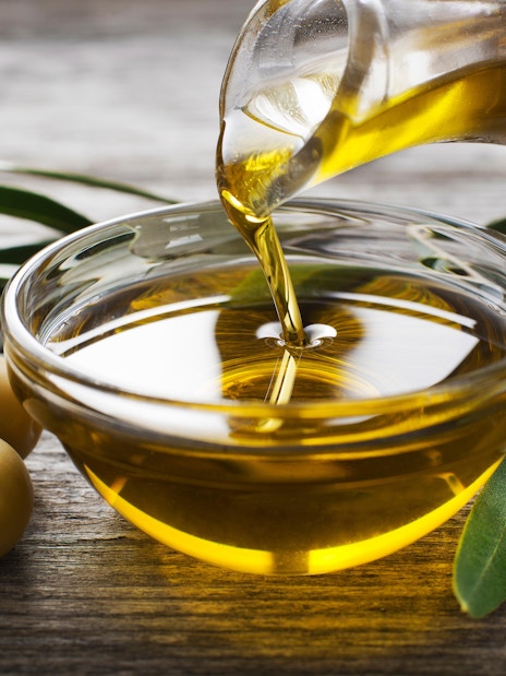 Pouring olive oil into a bowl with olives and leaves, Madrid shopping.