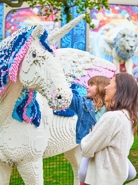 Child and adult admiring Lego unicorn at Legoland Windsor's Lego Mythica.