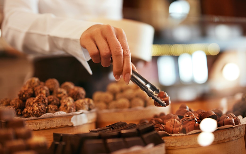 Hand selecting chocolates at Mr Bucket Chocolate Factory display.