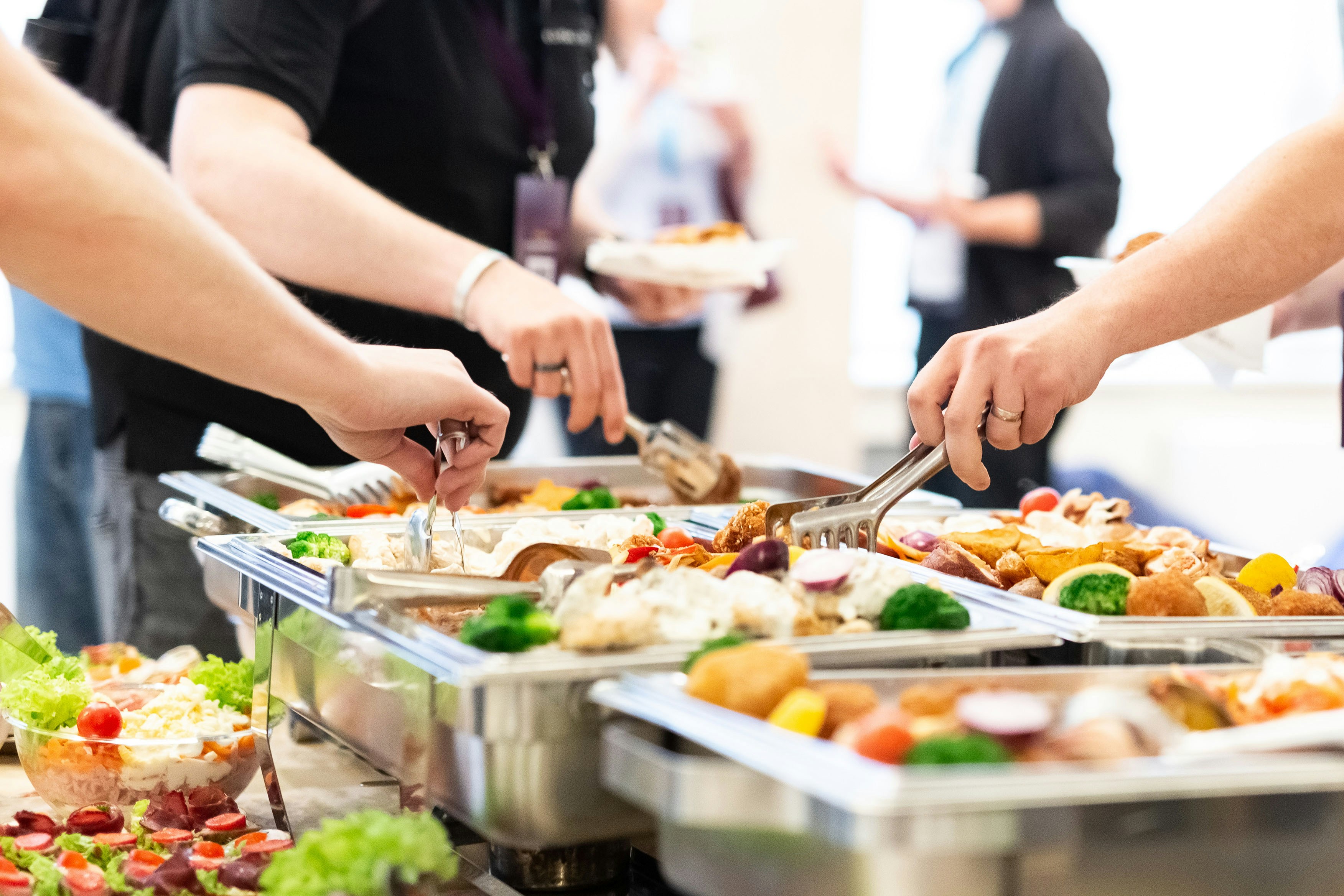 Tourists serving themselves at an all-you-can-eat buffet with diverse dishes.