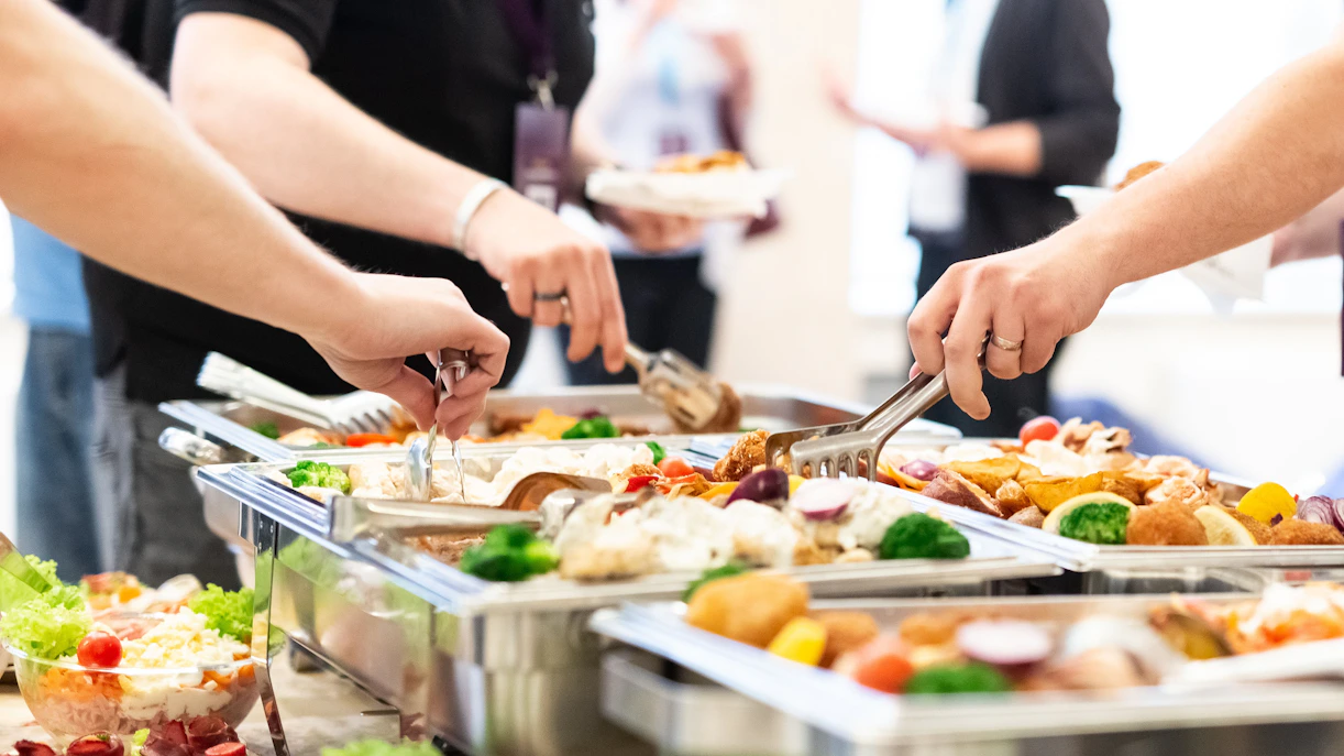 Tourists serving themselves at an all-you-can-eat buffet with diverse dishes.