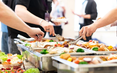 Tourists serving themselves at an all-you-can-eat buffet with diverse dishes.