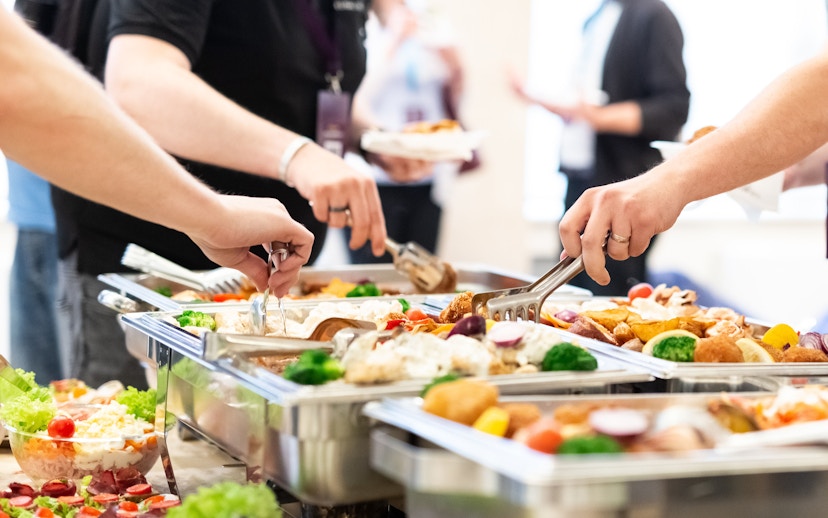 Tourists serving themselves at an all-you-can-eat buffet with diverse dishes.