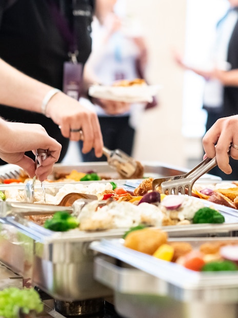 Tourists serving themselves at an all-you-can-eat buffet with diverse dishes.