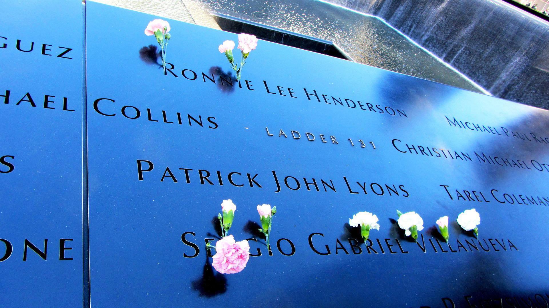 Names engraved on the 9/11 Memorial with flowers placed in remembrance.
