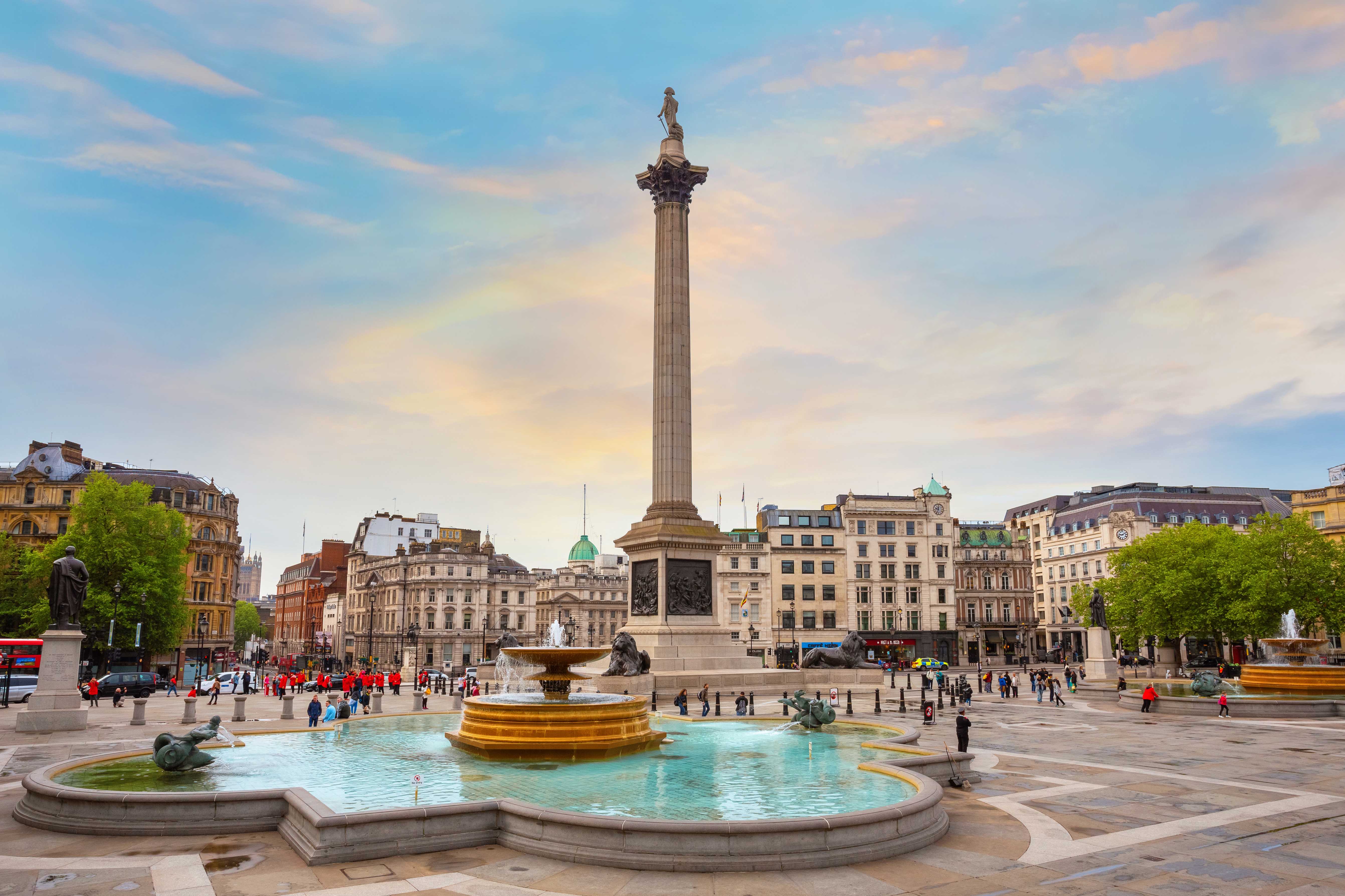 Trafalgar Square view from Hop-on Hop-off London bus with iconic red double-decker and Nelson's Column.