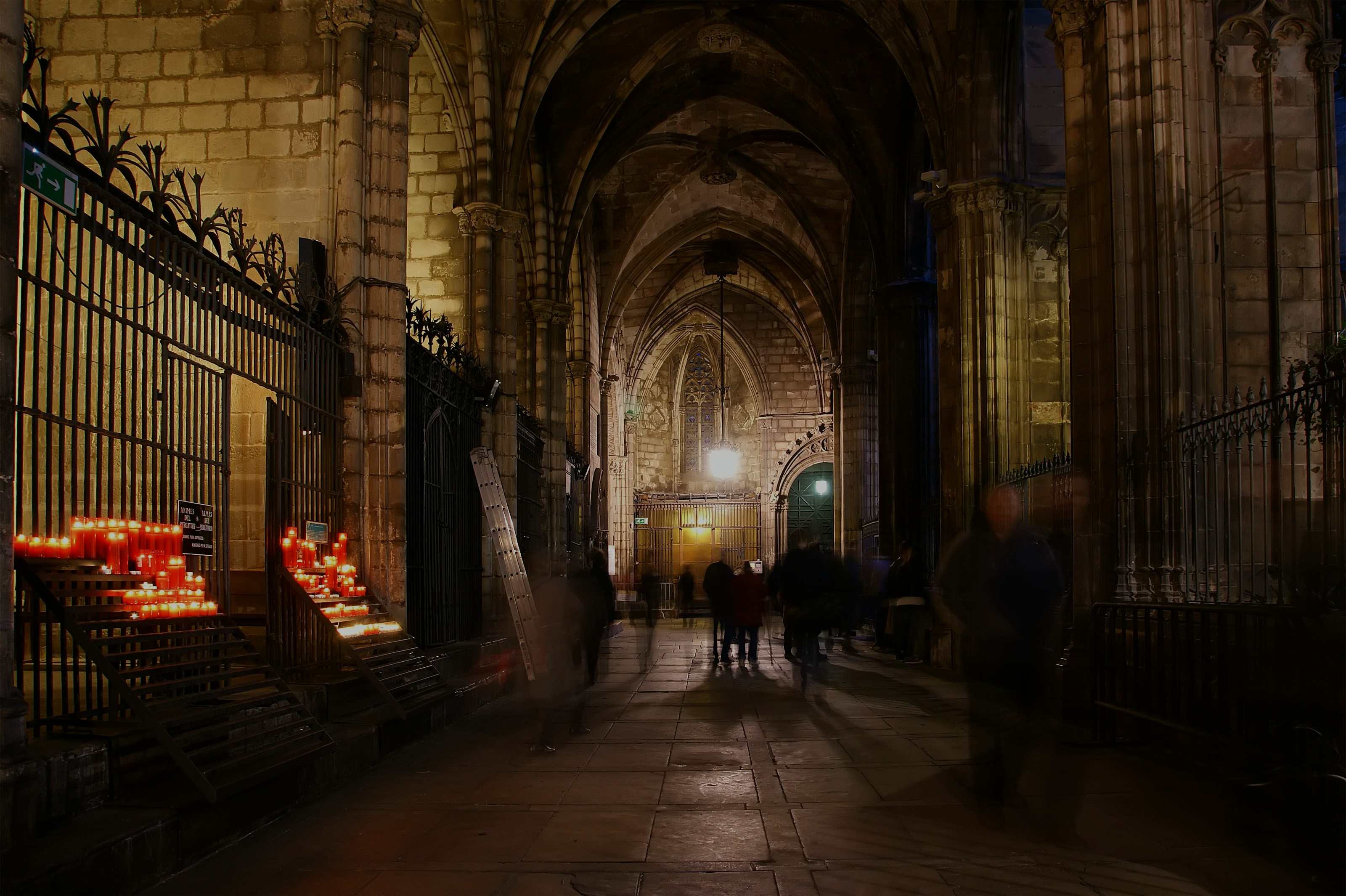 Sagrada Familia crypt interior with lit candles and visitors walking.