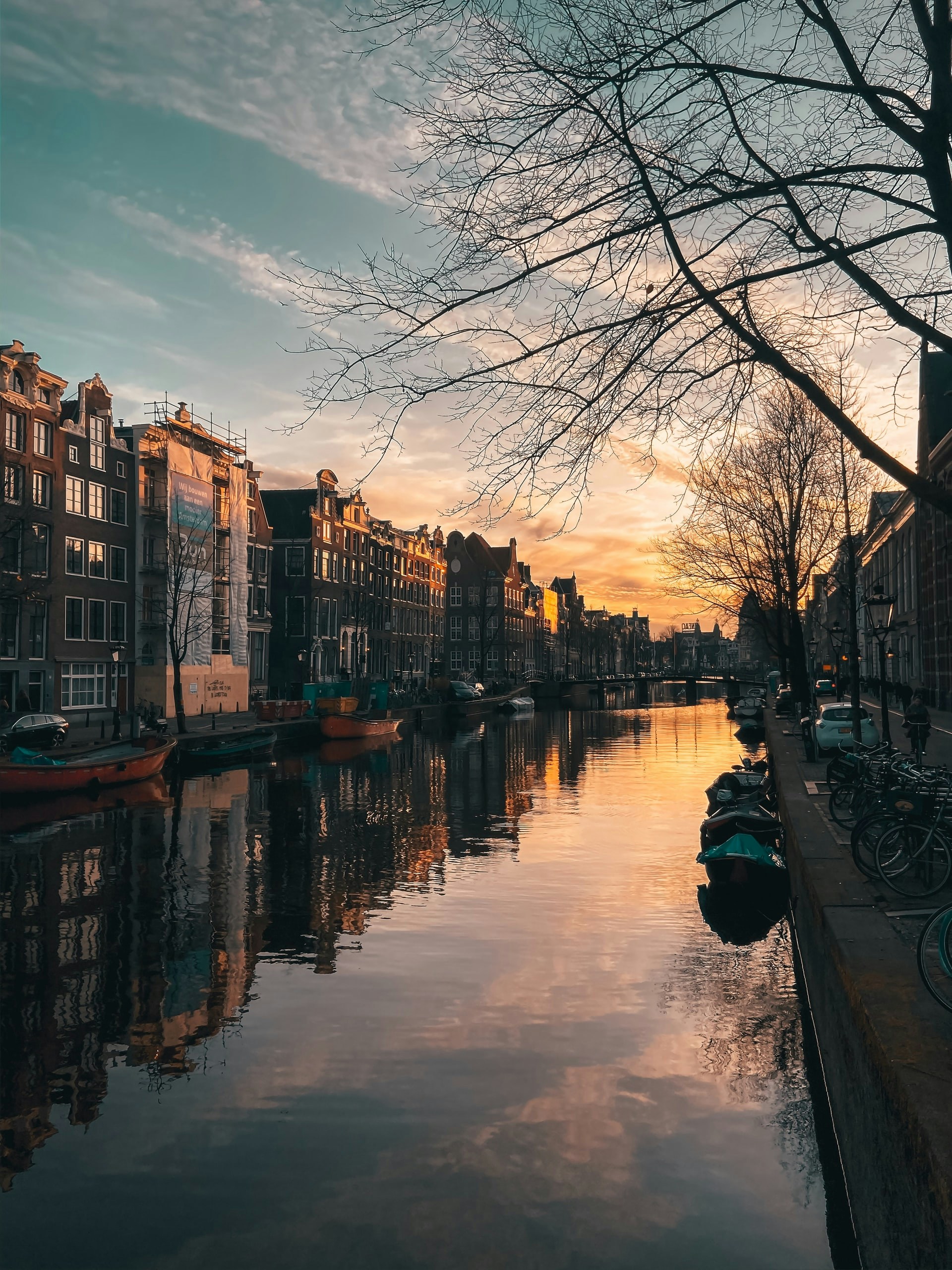 Amsterdam canal at sunset with boats along the Golden Bend.