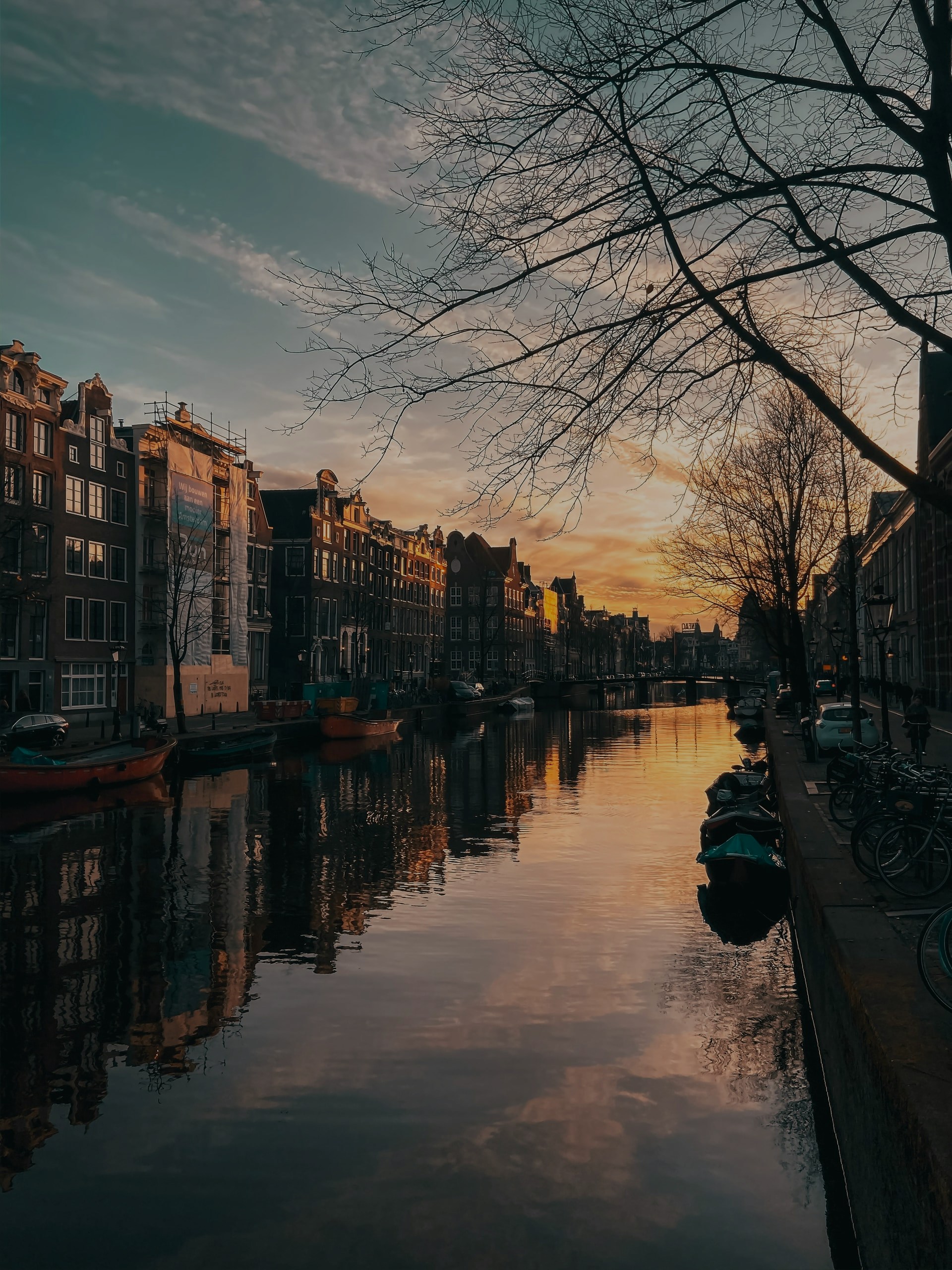 Amsterdam canal at sunset with boats along the Golden Bend.