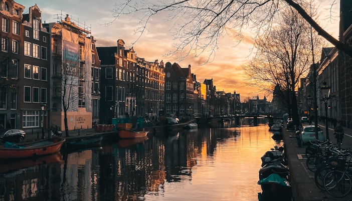 Amsterdam canal at sunset with boats along the Golden Bend.