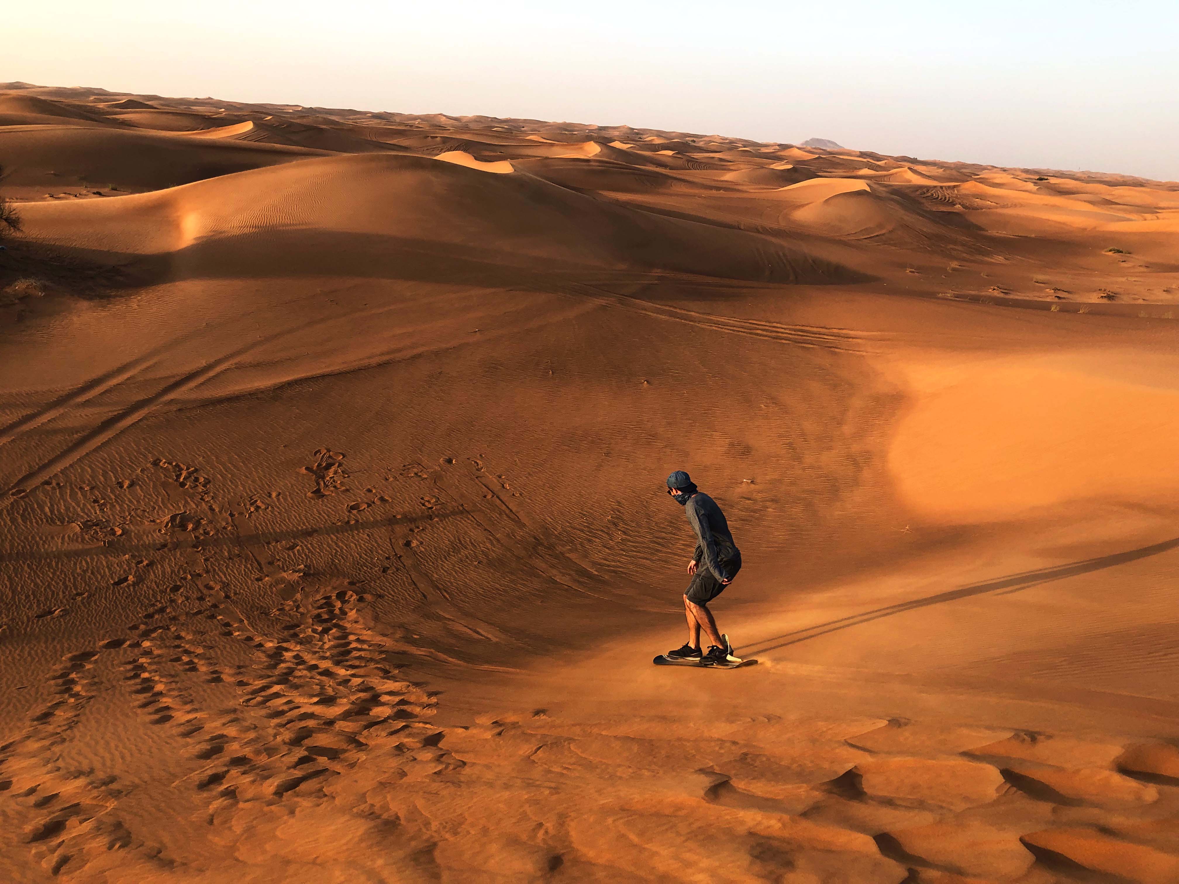 Sandboarding on dunes during Dubai Desert Safari.