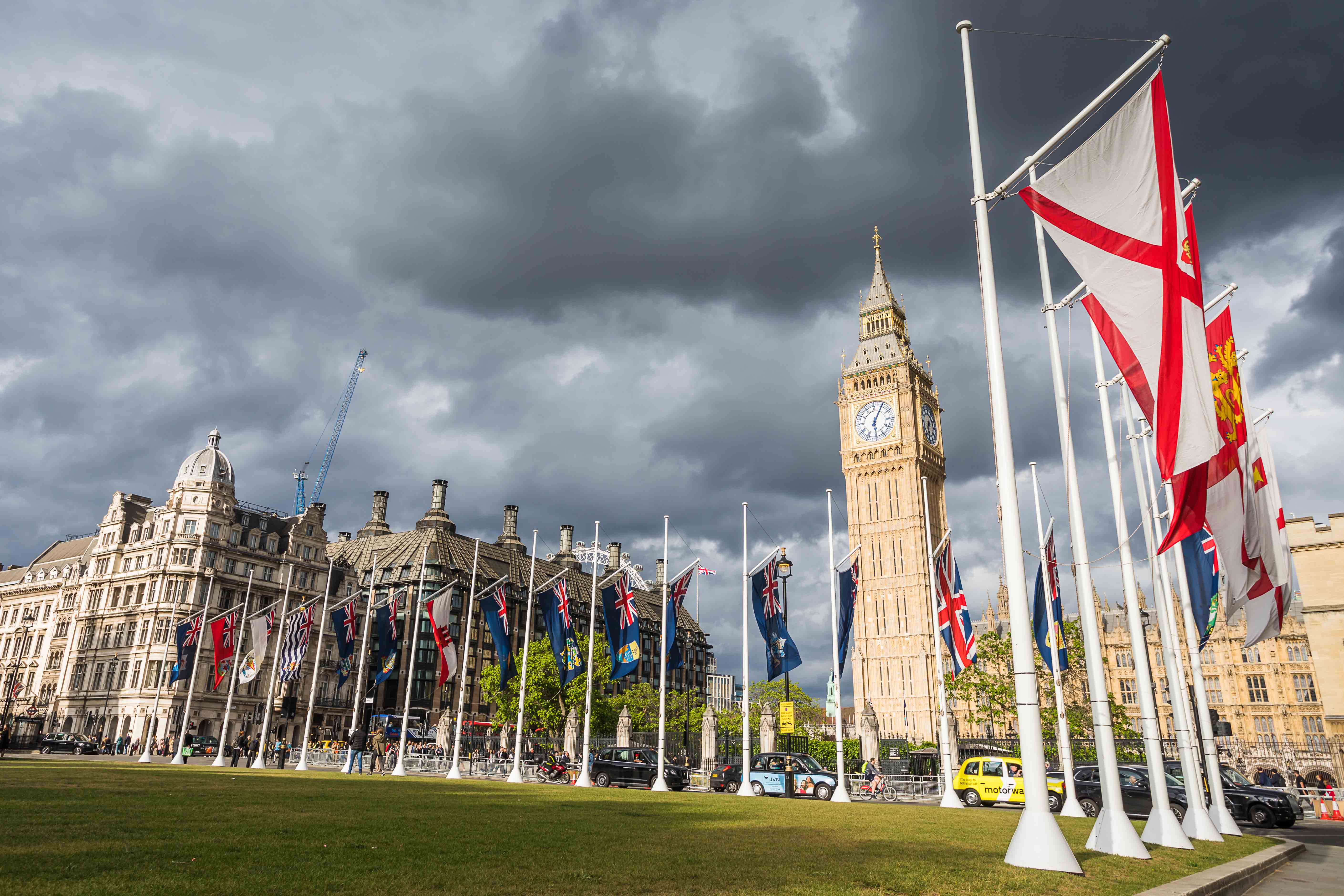 Flags and Big Ben at Parliament Square, London, on a cloudy day.