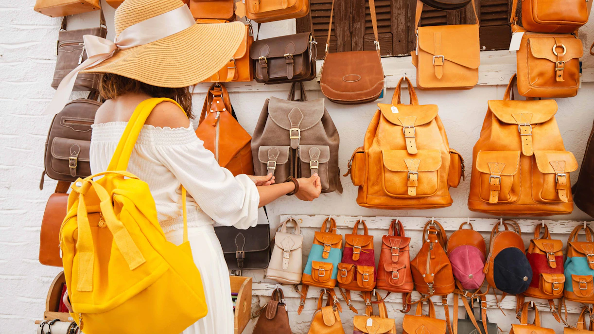 Shopper browsing handmade leather bags in Paris market.