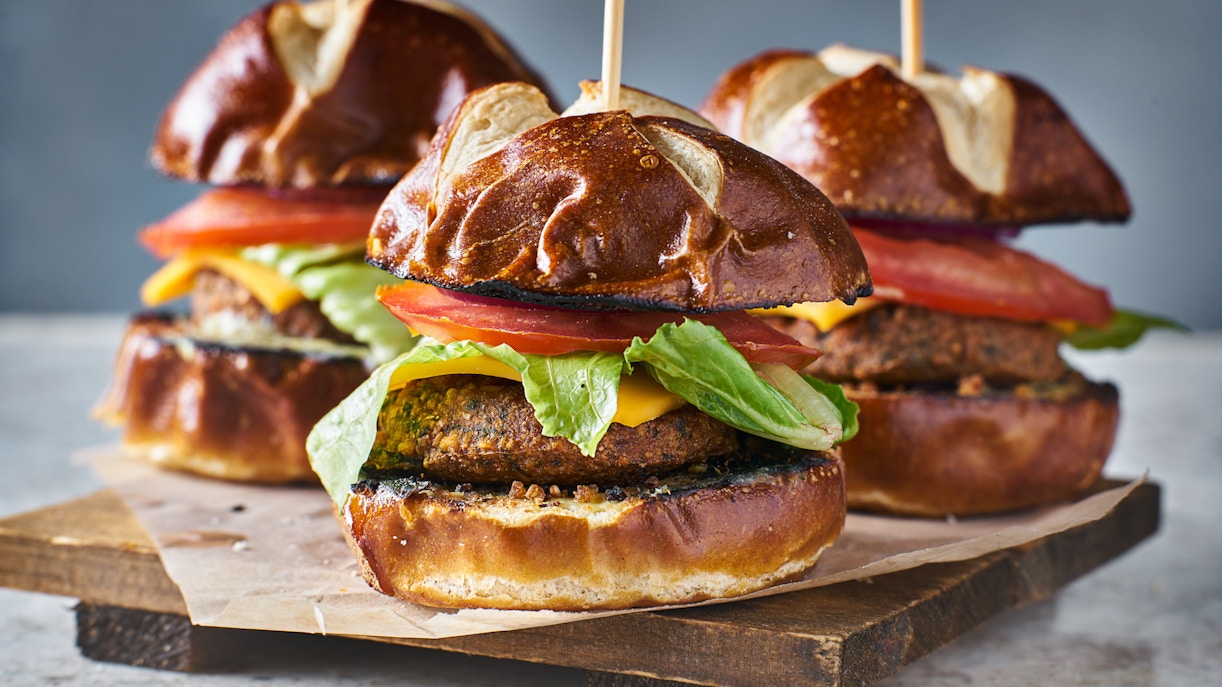 Sliders with lettuce, tomato, and cheese on pretzel buns, London street food.