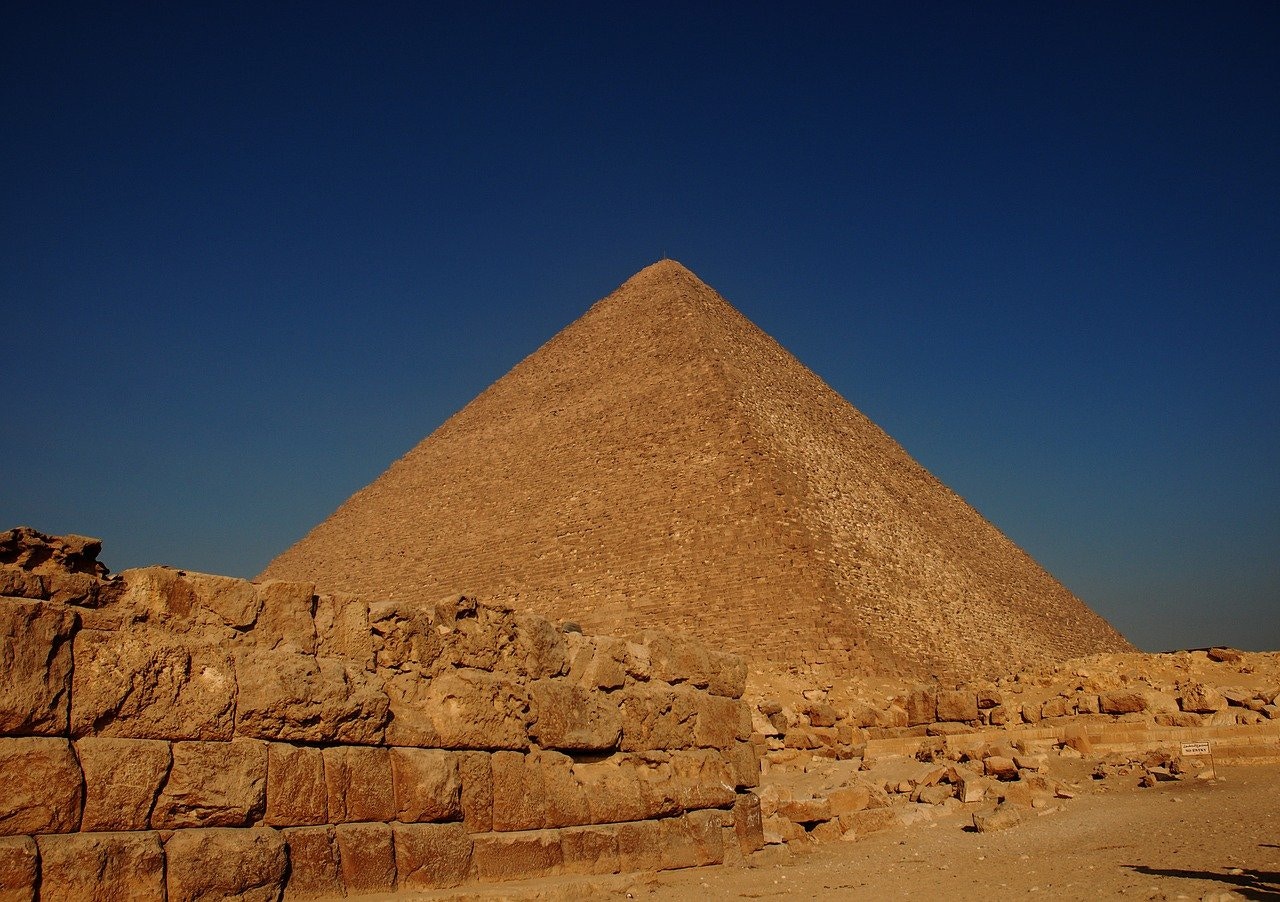 Khufu Pyramid at Giza with ancient stone ruins in foreground.