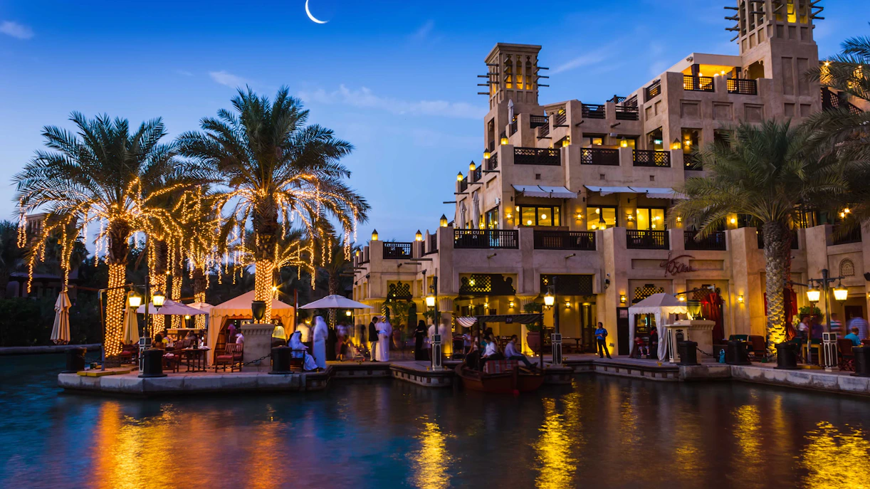 Madinat Jumeirah canal with lit palm trees and traditional architecture in Dubai.